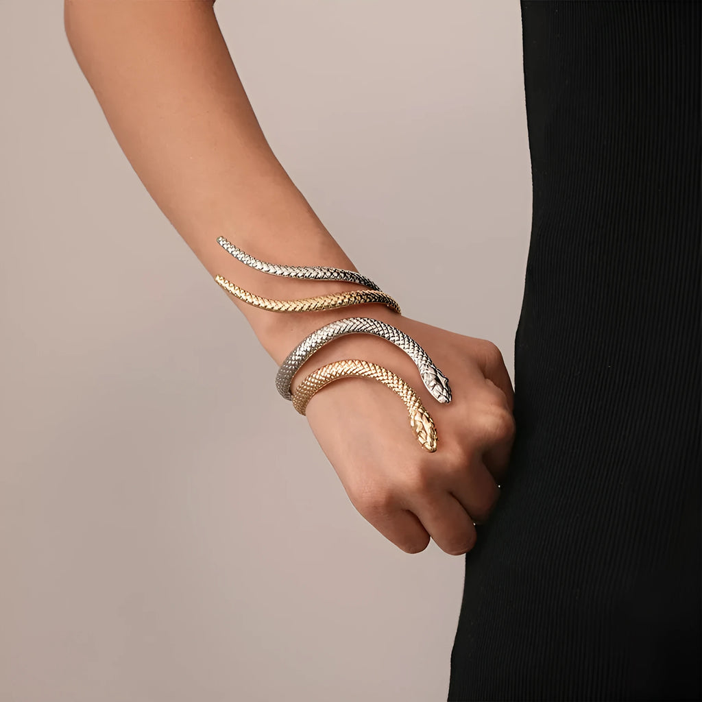 Gold exaggerated twisted snake design bracelet and ring jewellery set on a dark background.