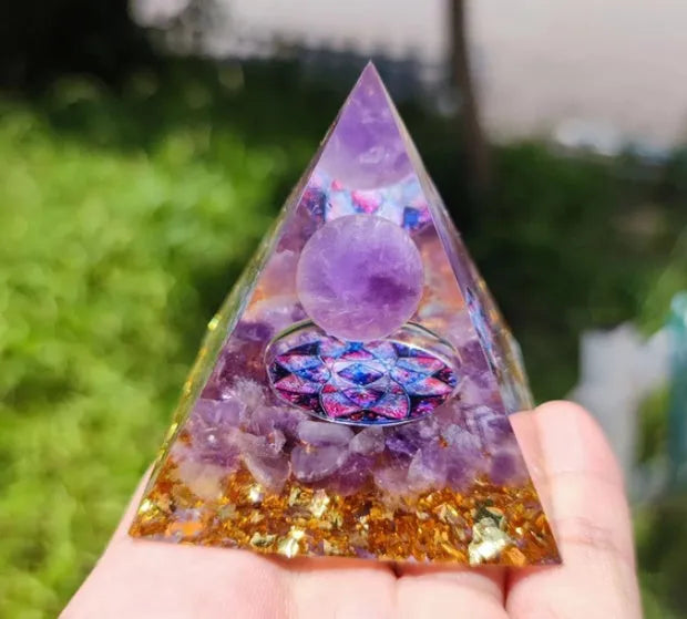 Clear epoxy resin pyramid ornament with natural crystal gravel inside on a wooden surface.