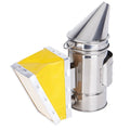 Stainless steel bee smoker with leather bellow on a wooden table against a blurred outdoor background