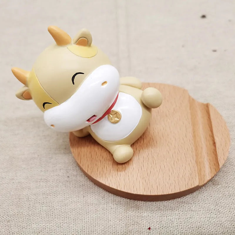 Beech wood and resin lazy bracket mobile phone holder in an animal design style on a desk.