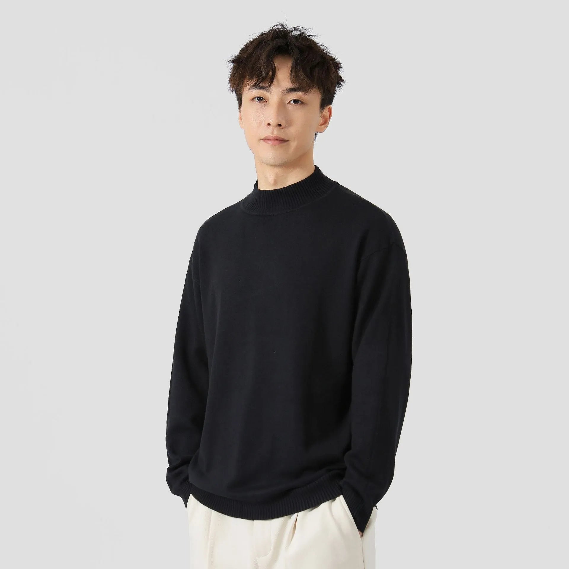 A man's loose-fitting, long-sleeve pullover sweater in a solid colour, showing a casual relaxed fit.