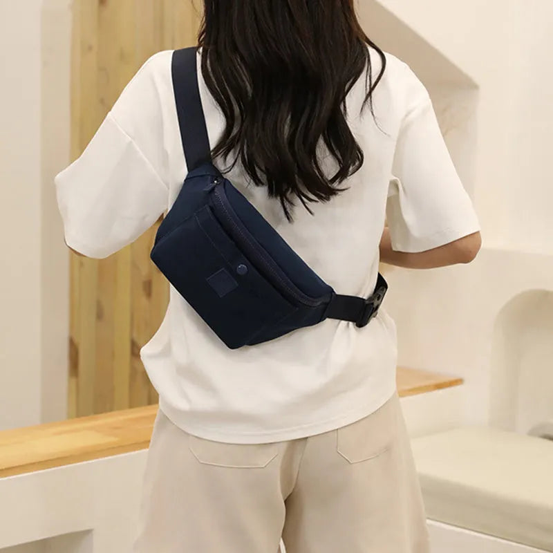 Women's nylon crossbody fanny pack in black with zippered compartments and letter detail.