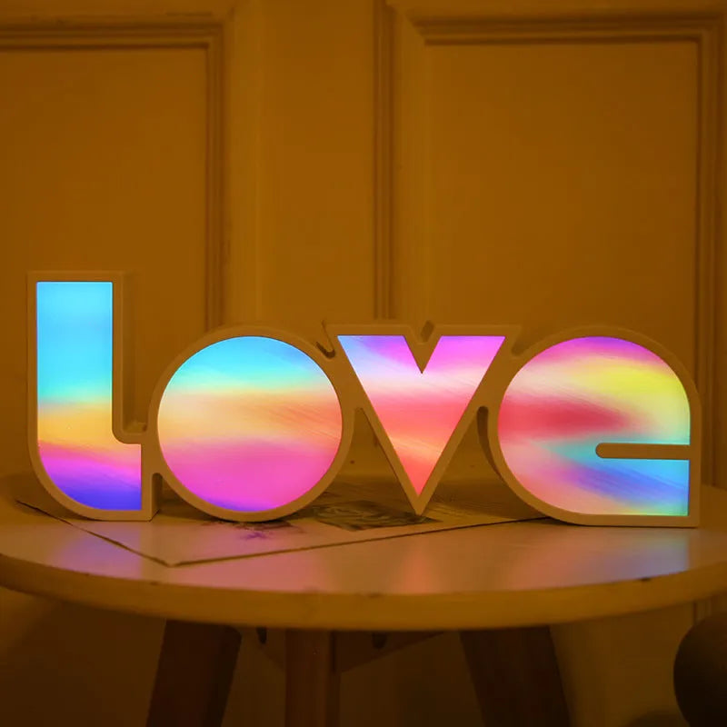 Colourful LED light spelling LOVE with rainbow lampshade, showing battery compartment and USB port