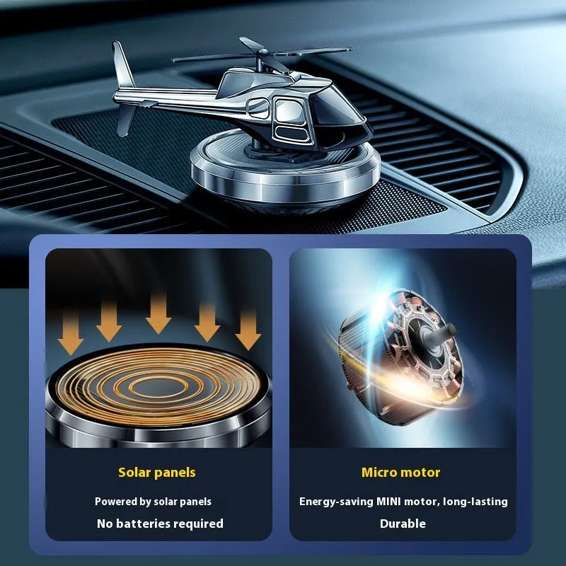 Silver solar-powered rotating metal car air freshener ornament on a dashboard.