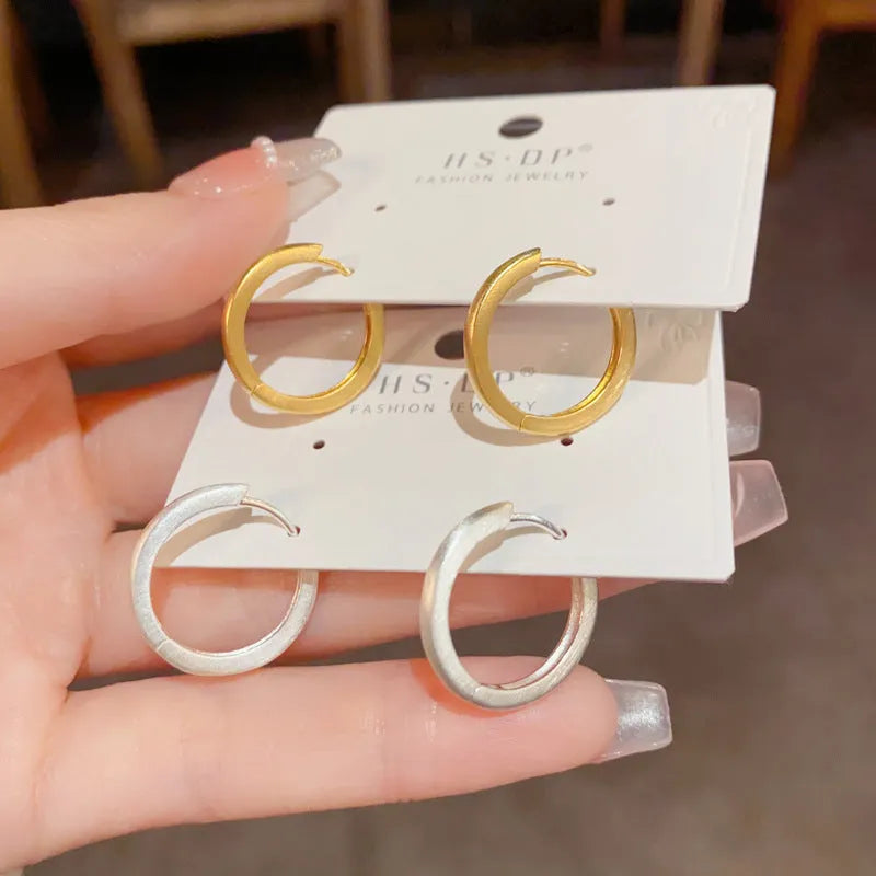 Women's geometric round eyelet ear clips in gold and silver colours, showing front view.