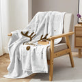 White flannel velvet deer antler pattern Christmas blanket on a sofa
