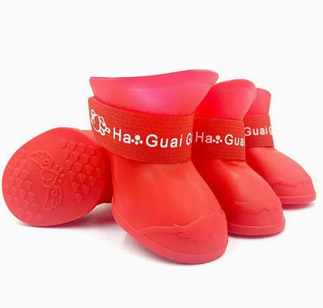 Set of four soft-soled rubber pet rain shoes in assorted colours on a grey background.