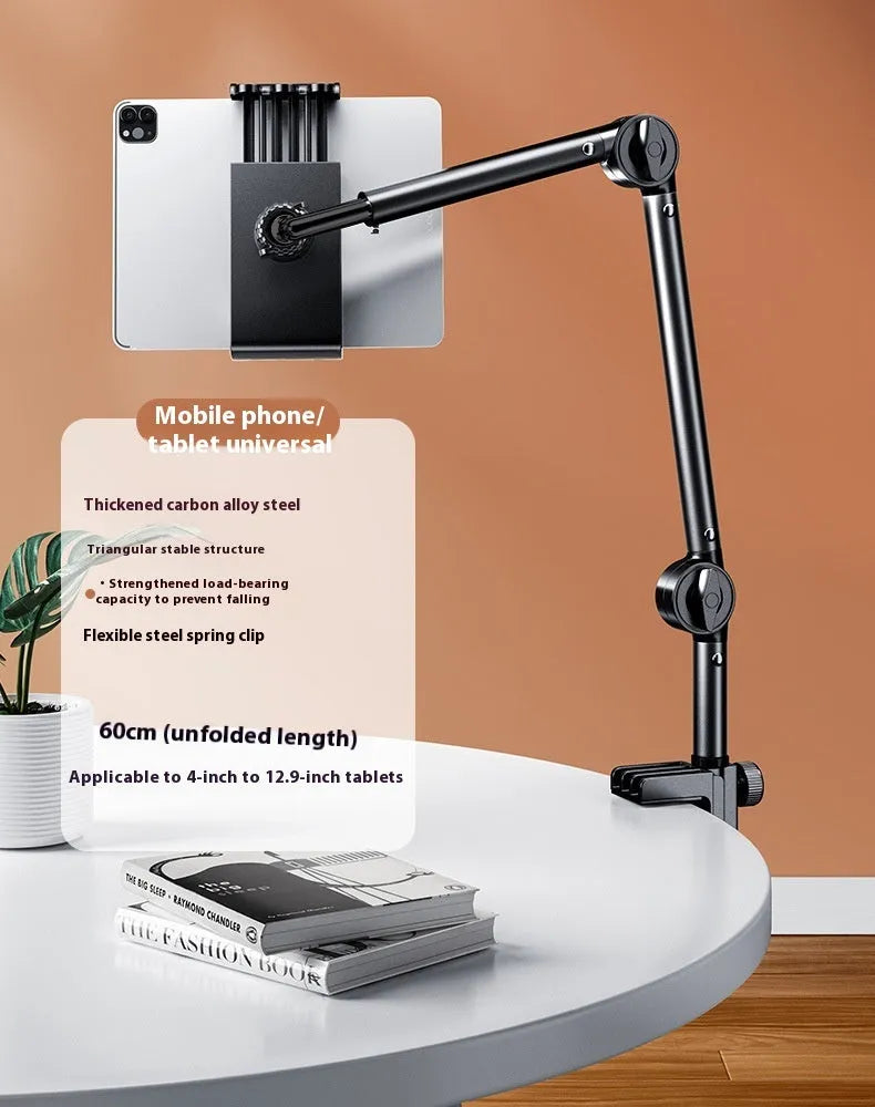 Silver alloy desktop phone and tablet bracket with double adjustable arms and a remote control on a wooden desk.