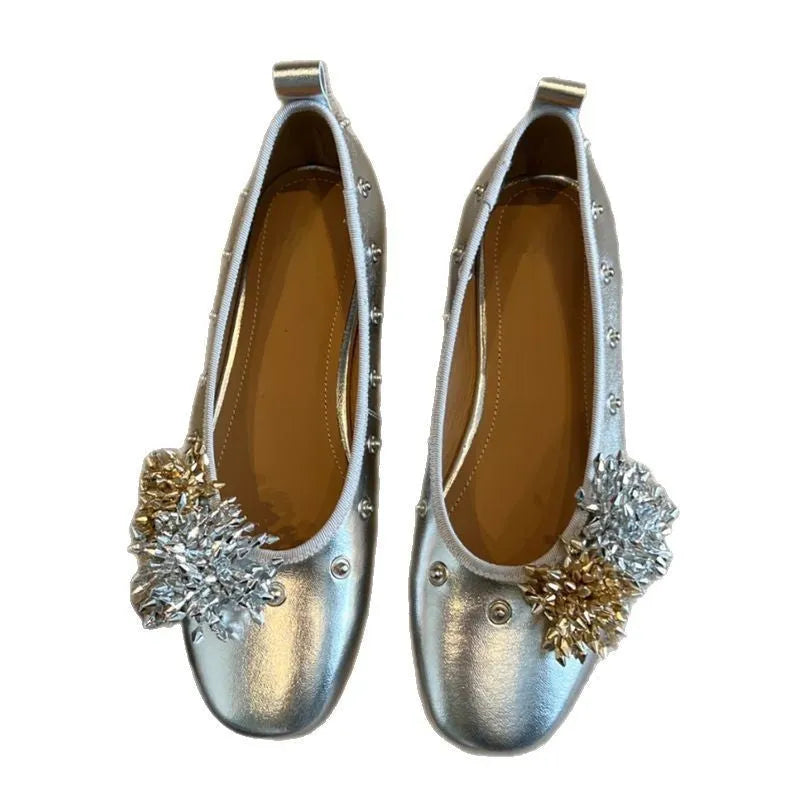 Women's silver Mary Jane flat shoes with flower rivets and a buckle strap on a sheepskin upper.