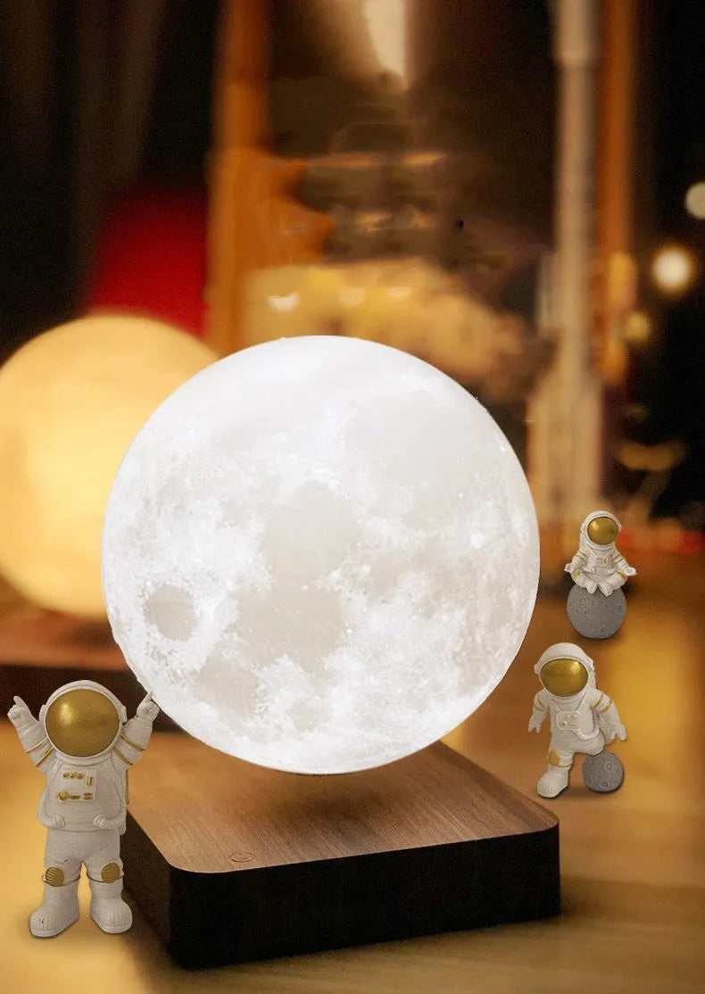 Moon planet floating LED night light with three astronaut figurines on dark surface