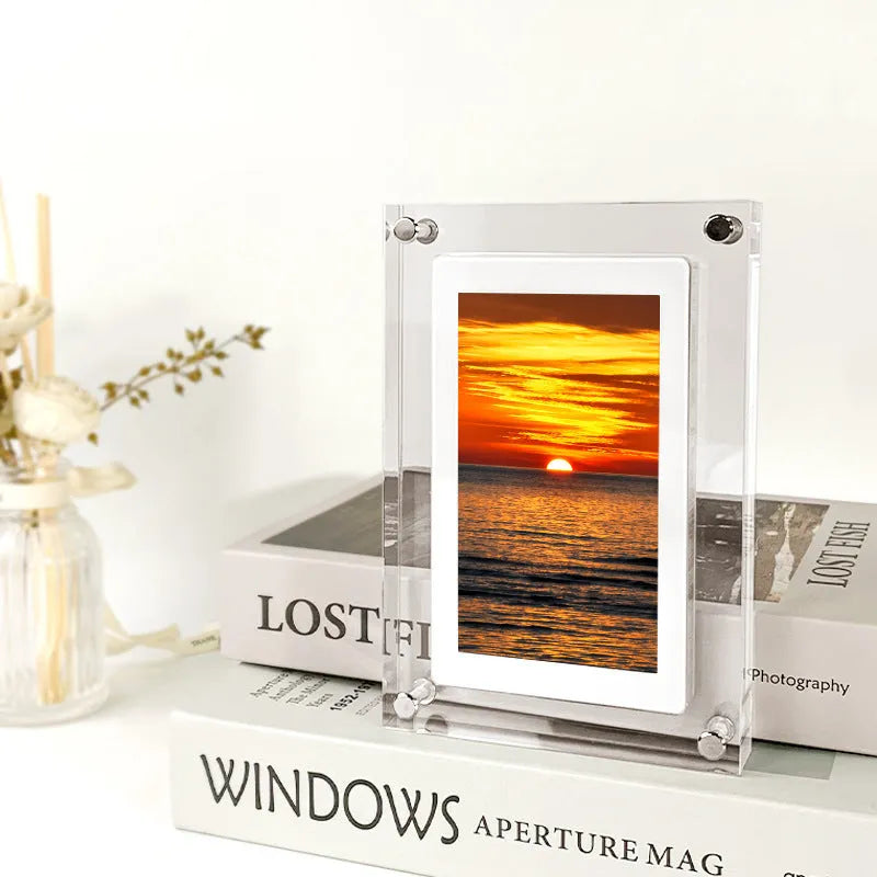 White vertical digital picture frame with acrylic casing on a table, showing a family photo on screen.