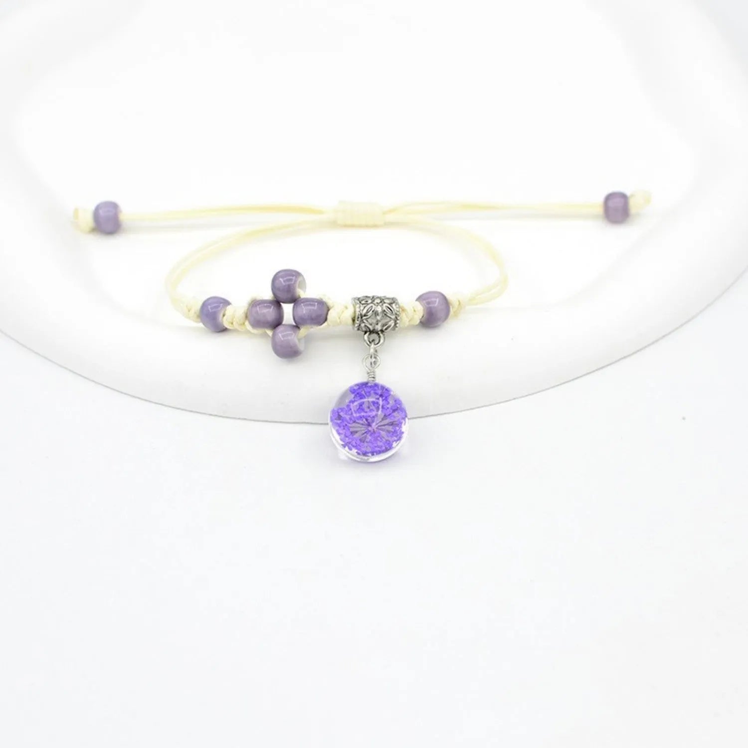 Close-up of a hand-woven glass bracelet with large 1.4cm beads containing real dried flowers in various colours.
