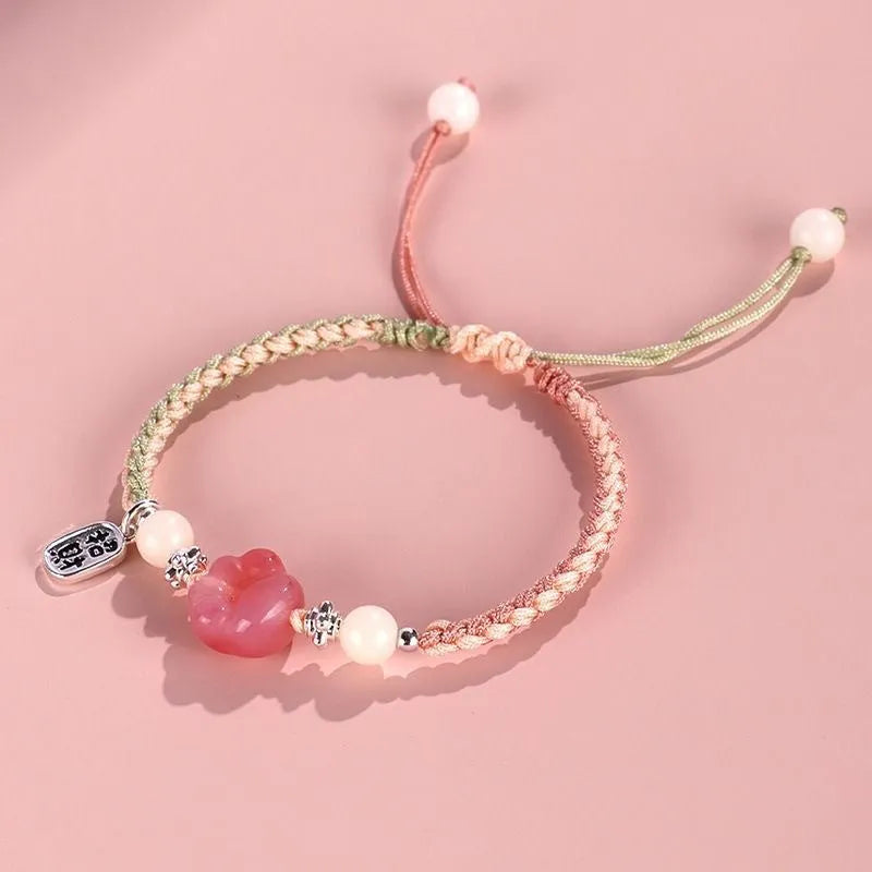 Red cat's paw glass bead on a handmade pink woven bracelet for couples.