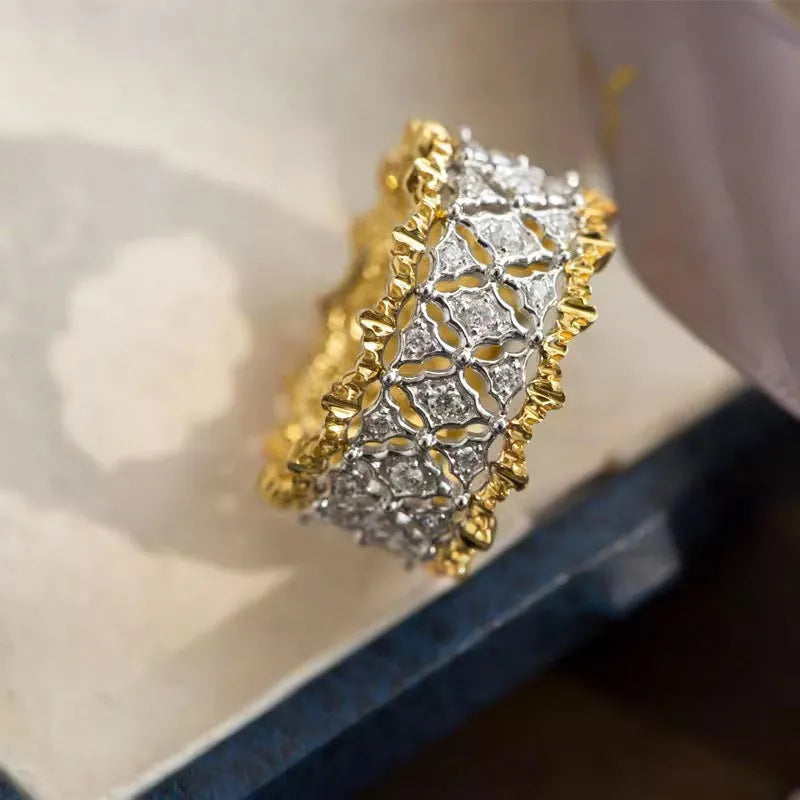 Geometric two-tone gold zircon ring on a plain background showing its round centrepiece and band detail