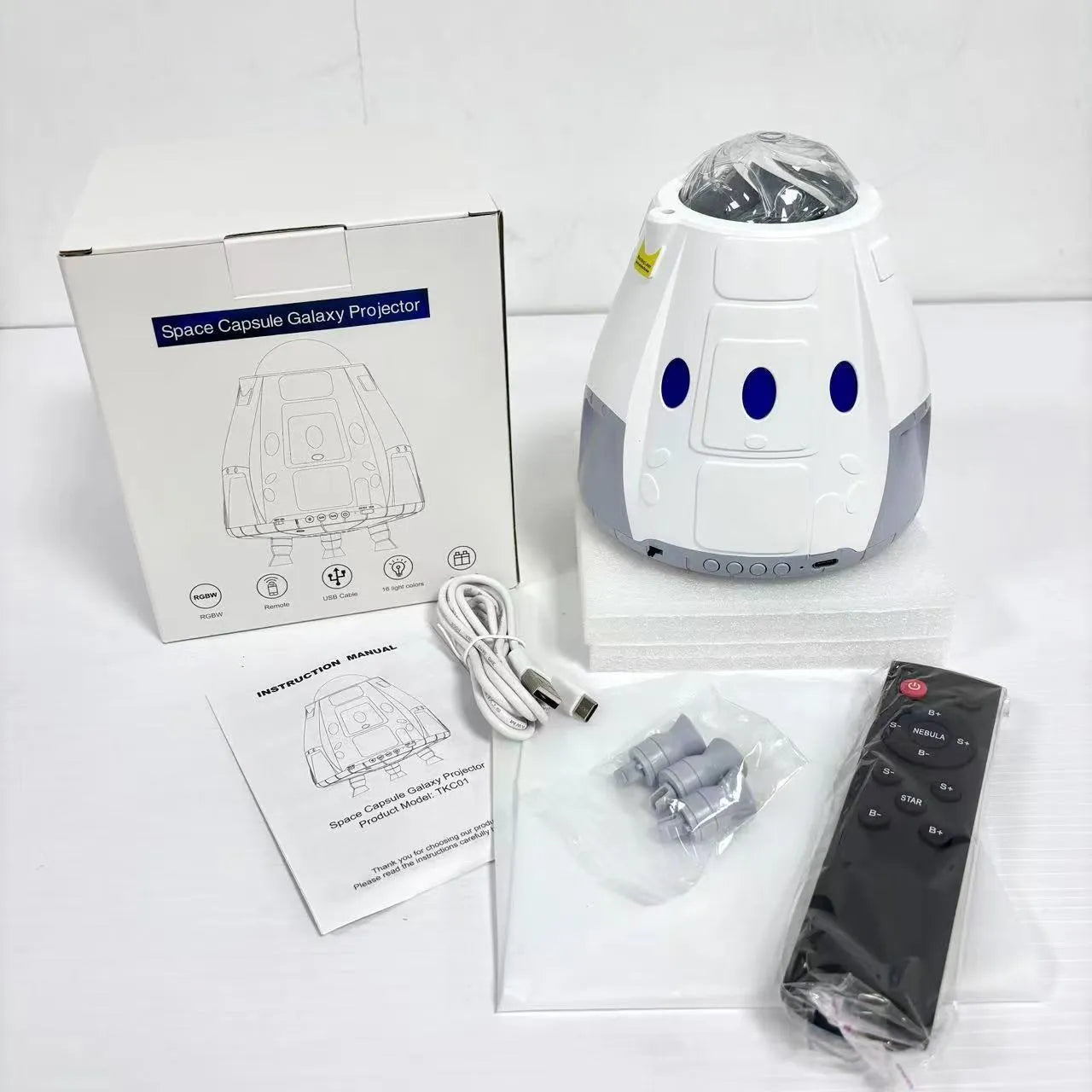Space capsule shaped projection lamp showing galaxy lighting effects on wall, available in Space Grey or Space White finish