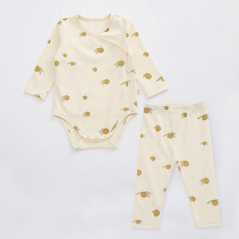 Newborn baby cotton romper two-piece suit in neutral style with top, pants, and matching hat on a white background
