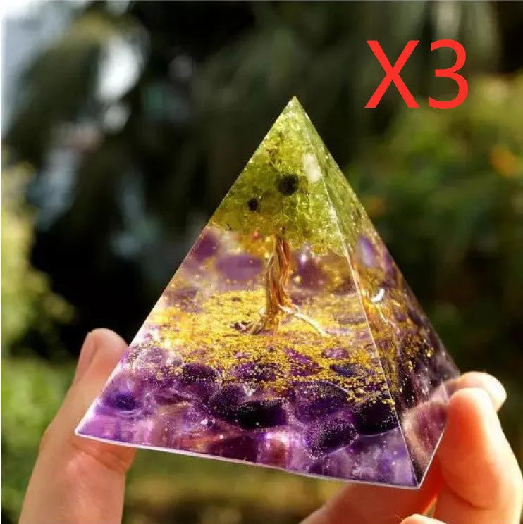 Clear epoxy resin pyramid ornament with natural crystal gravel inside on a wooden surface.