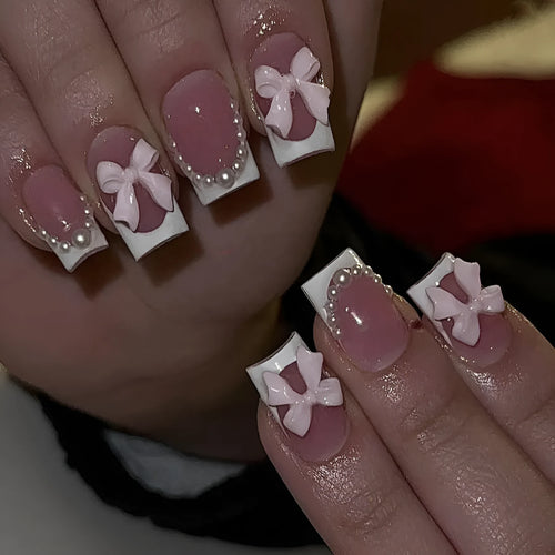 Artificial press-on nails with French manicure style showing bow patterns and tulip designs on short European square nails
