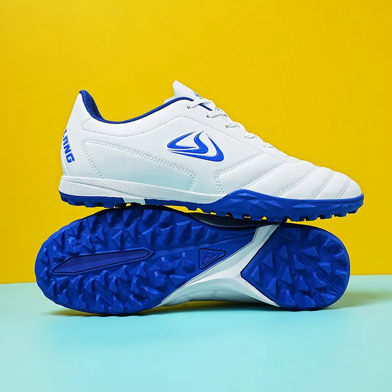 Low-top outdoor soccer shoes in a black and blue broken nails colourway on a turf background.