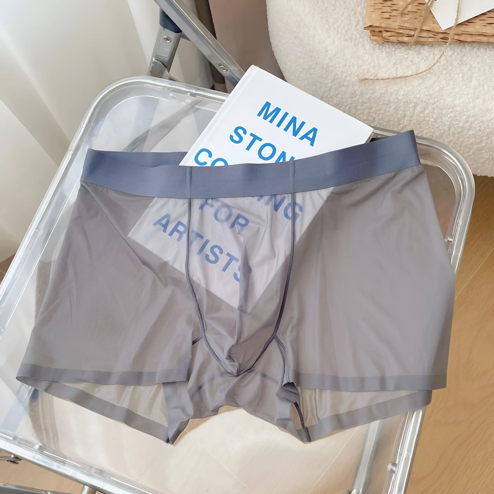Men's thin grey seamless nylon boxer shorts laid flat, showing mid-waist and body-shaping design.