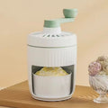 Hand-cranked ice shaving machine in green and orange, compact portable snow cone maker with ergonomic handle and removable ice box.