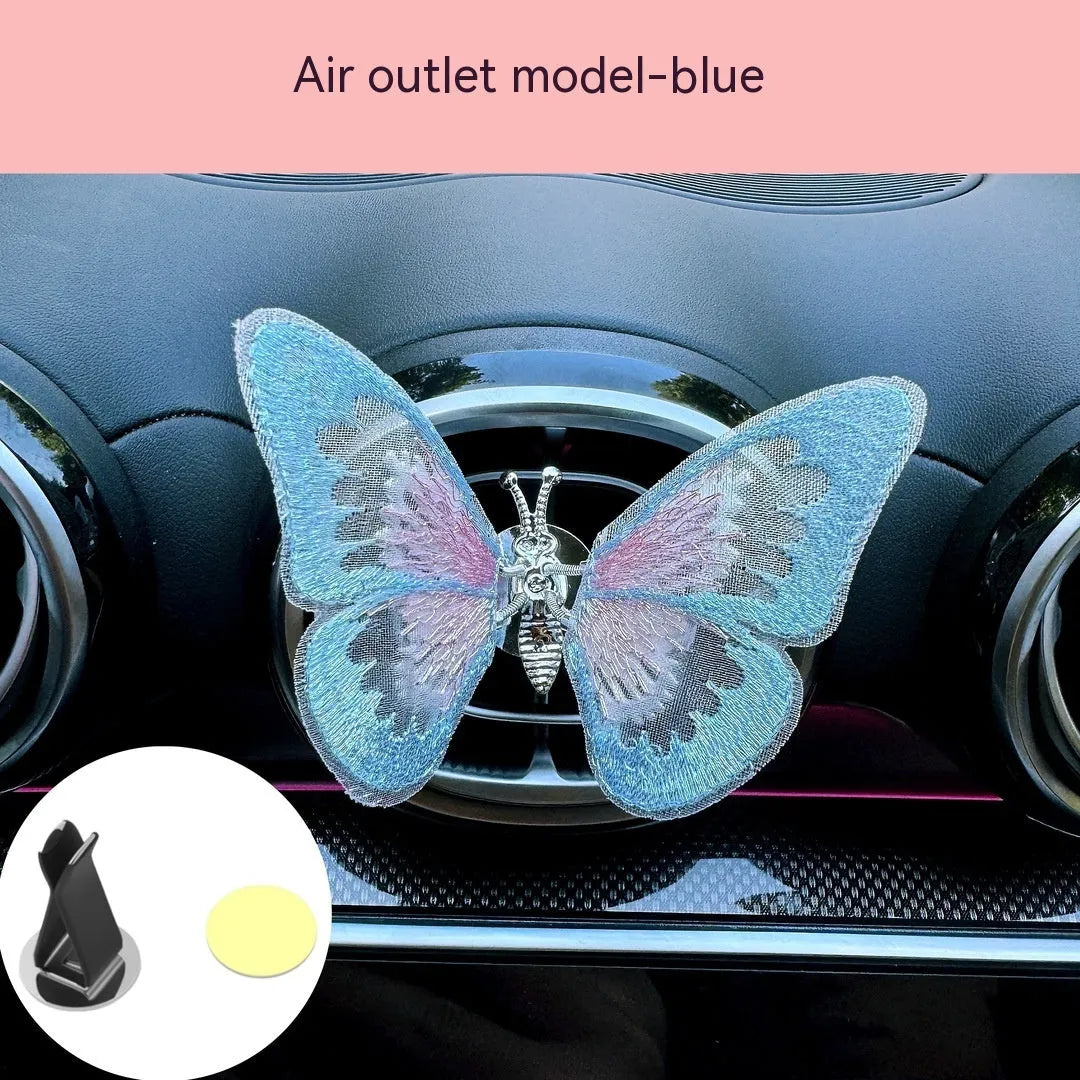 Fabric embroidered butterfly car air vent decoration in multiple colour options on a dashboard.