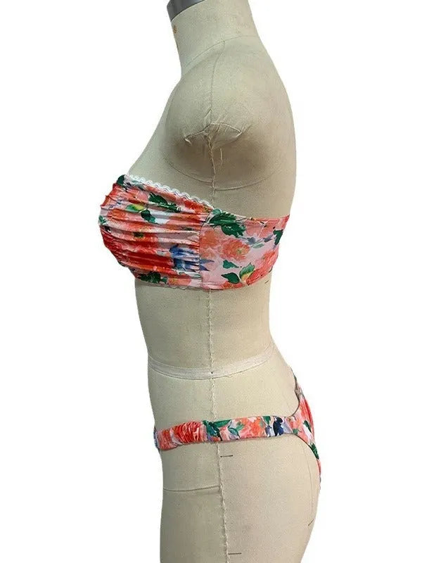 Women's floral print tube top bikini set with lace detailing on a blue background.