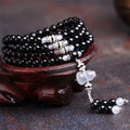 Natural red and black agate stone beaded bracelet with 108 geometric beads on a wrist.