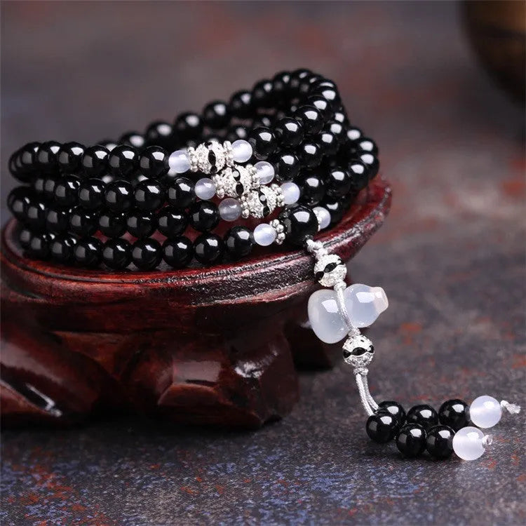 Natural red and black agate stone beaded bracelet with 108 geometric beads on a wrist.