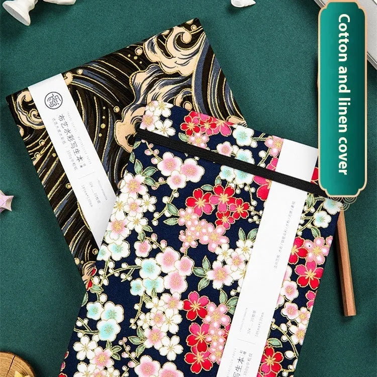 Feiluniao handmade fabric watercolour notebook with illustrated cover, open to show blank paper pages.