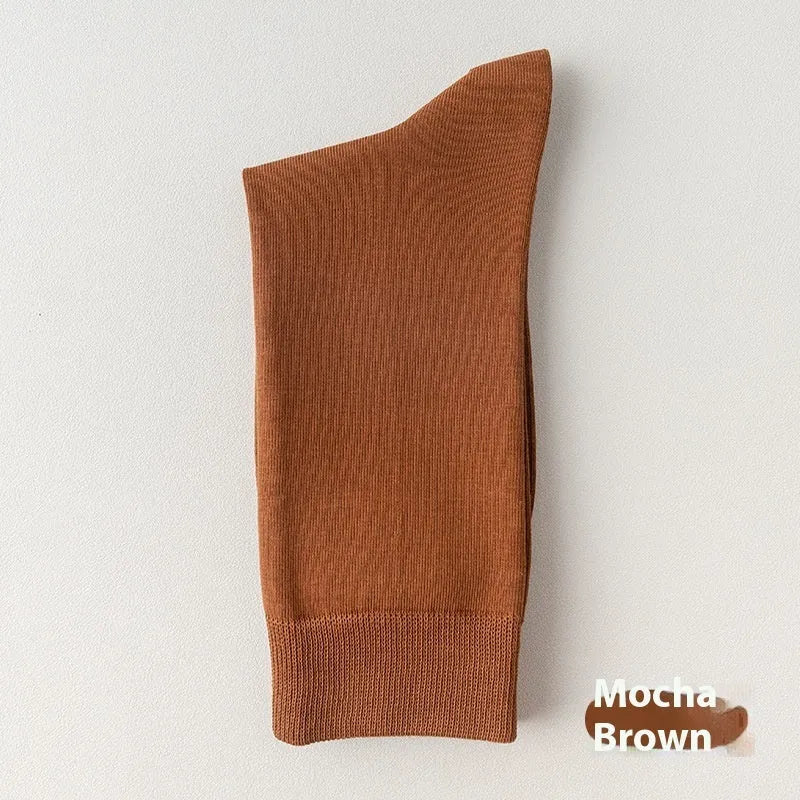 Five pairs of men's solid colour mid-calf socks made from combed cotton, shown in assorted shades.