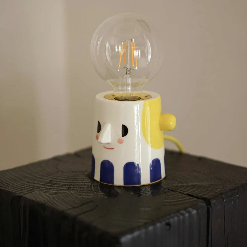 Handmade ceramic table lamp with a white ball headlight shade on a wooden table.