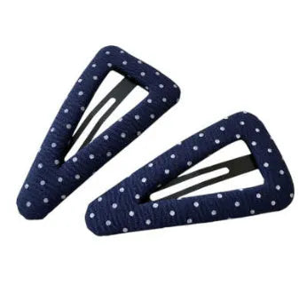 Dark denim barrette with white polka dots in a triangle shape next to a water drop shaped barrette.