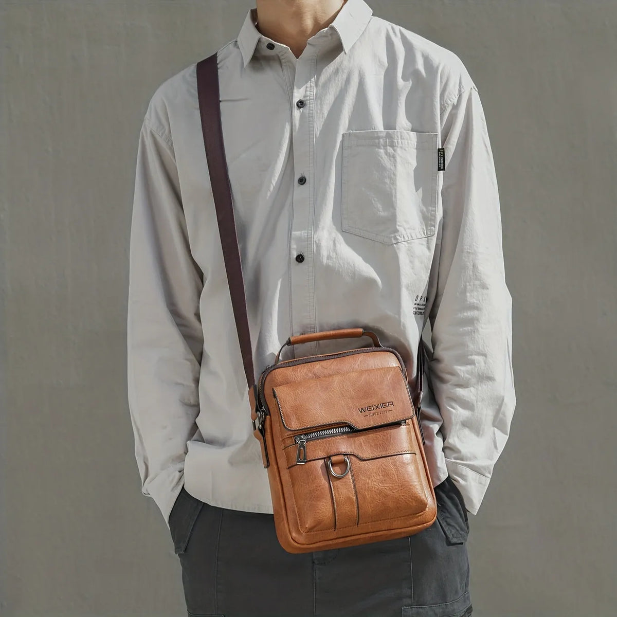 Men's brown PU leather crossbody messenger bag with metal zipper and adjustable strap on a plain background