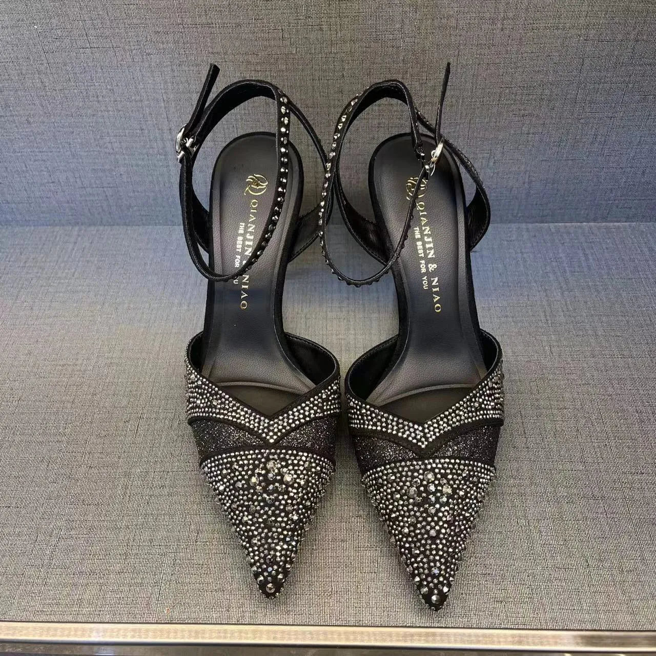 Black women's stiletto high heel shoe with a pointed toe and a bright red sole.