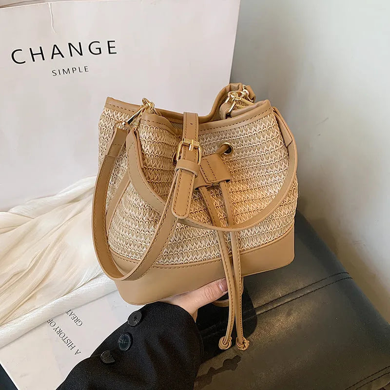 Brown woven straw women's crossbody bucket bag with a long adjustable strap.