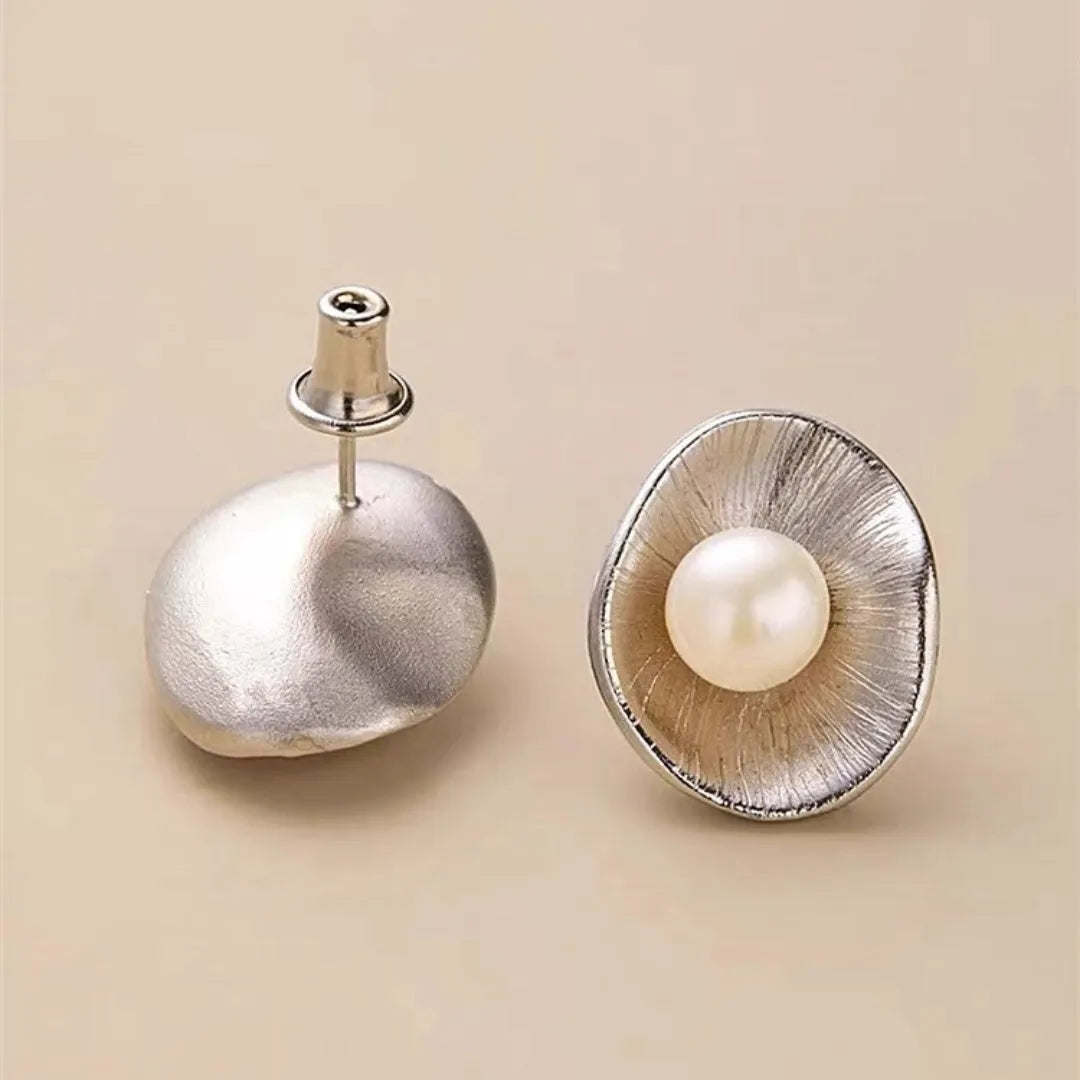 A pair of sterling silver geometric stud earrings featuring a central simulated pearl.