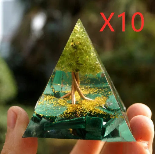 Clear epoxy resin pyramid ornament with natural crystal gravel inside on a wooden surface.