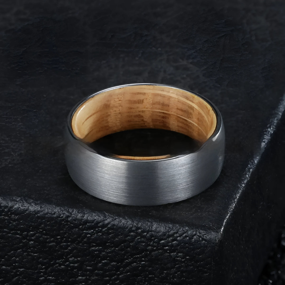 Silver tungsten ring with barrel wood inlay for men, simple band on light background