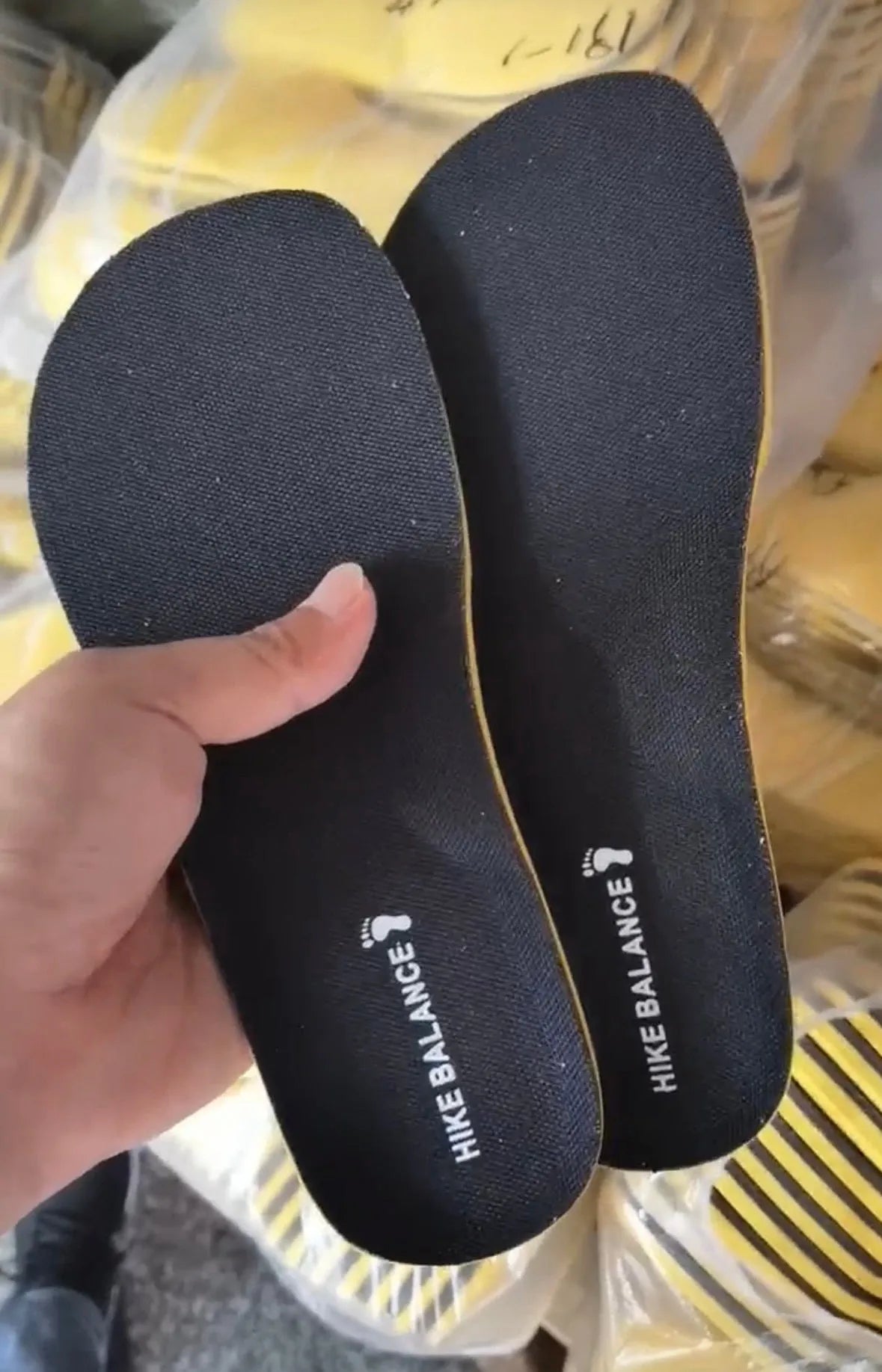Pair of black soft sports shock-absorbing polyester insoles on a light background