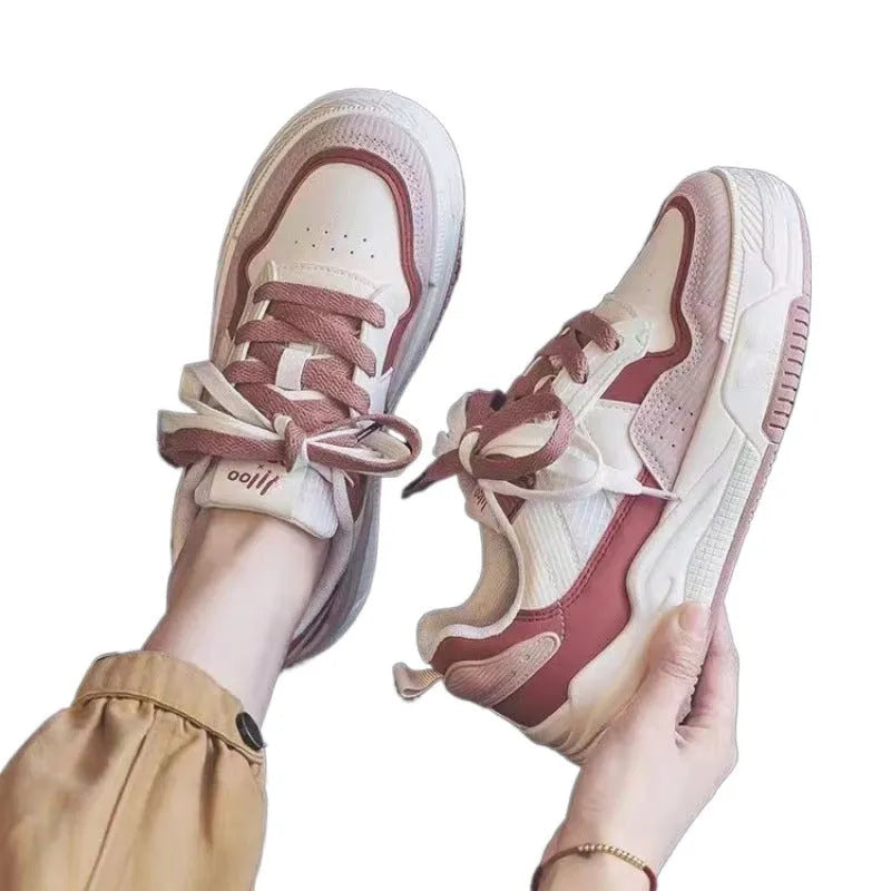 Women's pink and white low-top sneakers with a height-increasing rubber sole on a neutral background.