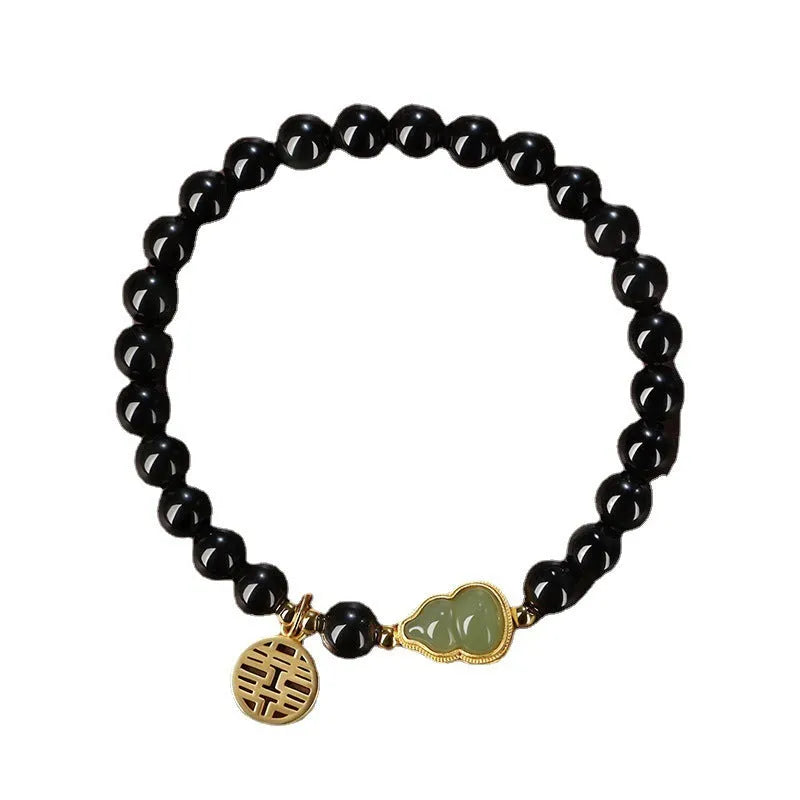 Black obsidian bead bracelet with a carved Hetian jade gourd charm, shown in geometric retro style.