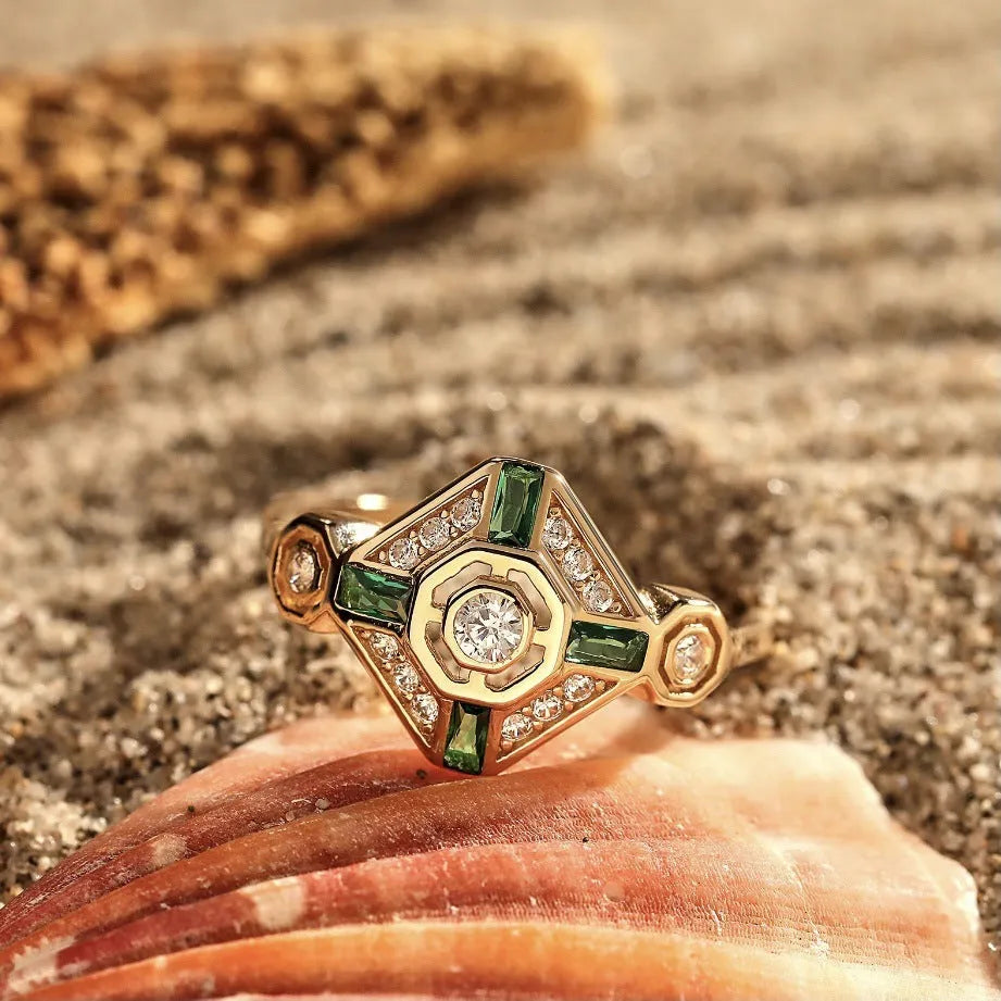 Square-shaped gold tone ring with emerald diamond colour on a model finger.