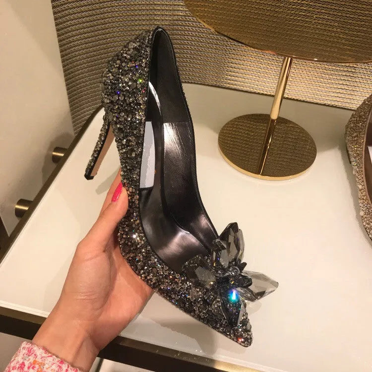 Gold women's pointed toe high heels with rhinestone and sequin decorations on a stiletto heel.