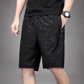 Man wearing loose fit black polyester sports shorts with elastic waistband