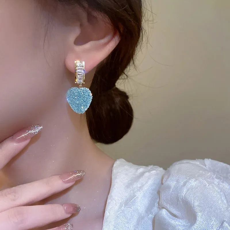 Close-up of women's cute alloy candy stud earrings with a peach heart design in pink and blue.