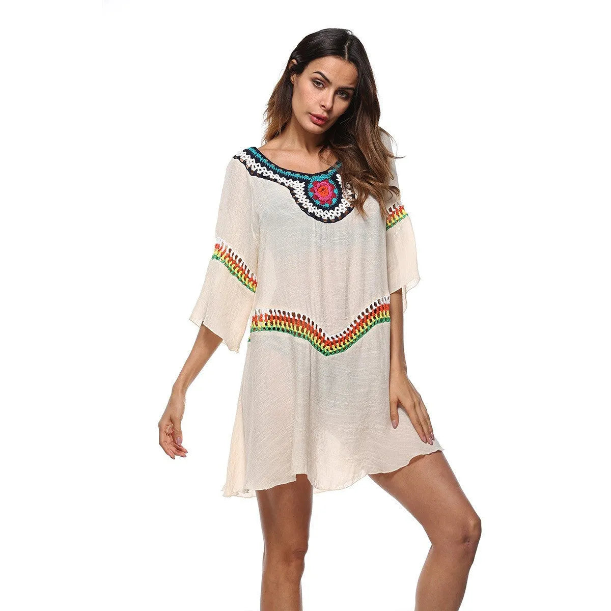 Woman wearing a crocheted white sun protection beach cover-up by the water.