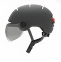 Adult cycling helmet with integrated red LED brake and tail light on the back, shown in sizes M and L.