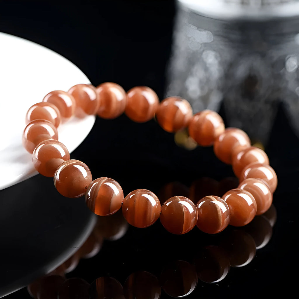 Natural old mine rhodochrosite round bead bracelet with Ruyi detail on a wrist.