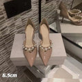Women's black patent leather stiletto high heels with pointed toe and pearl decoration on display.
